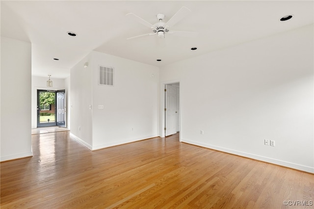 empty room featuring light wood finished floors, visible vents, ceiling fan, and baseboards