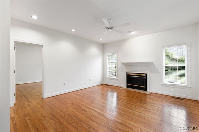 unfurnished living room with a glass covered fireplace, light wood-style flooring, recessed lighting, and a ceiling fan