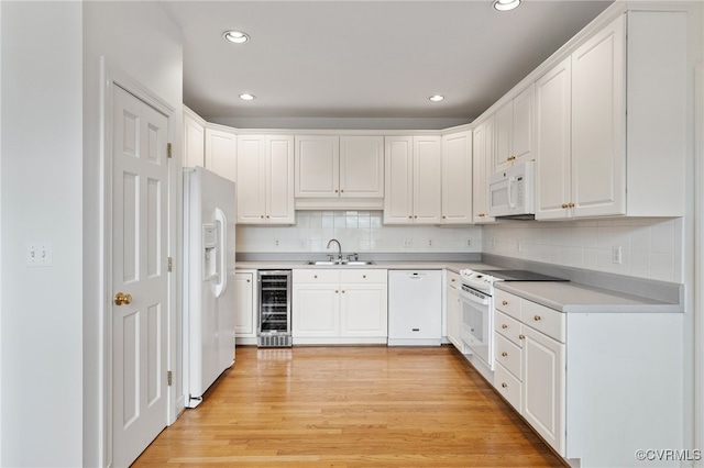 kitchen with wine cooler, light wood-type flooring, white appliances, white cabinetry, and a sink