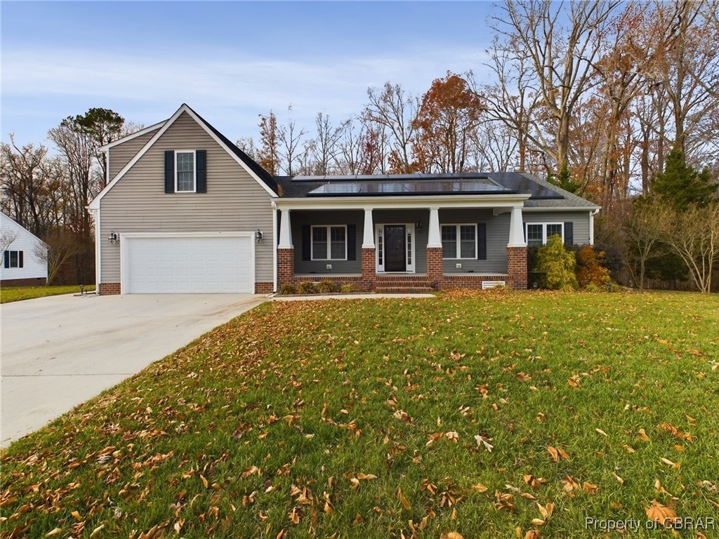 view of front of home featuring covered porch, a garage, and a front lawn