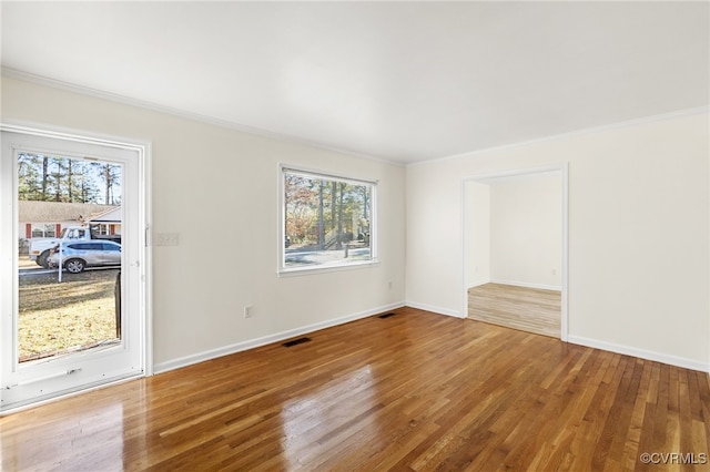 spare room featuring plenty of natural light, wood-type flooring, and ornamental molding