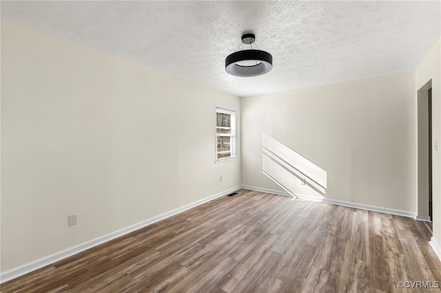 unfurnished room with hardwood / wood-style floors and a textured ceiling