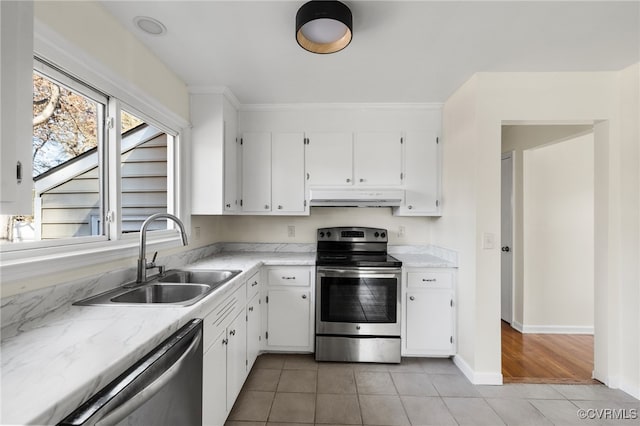 kitchen with appliances with stainless steel finishes, light tile patterned floors, white cabinetry, and sink