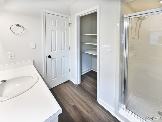 bathroom with hardwood / wood-style floors, vanity, and a shower with shower door
