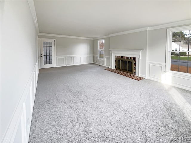 unfurnished living room featuring carpet flooring, crown molding, and a brick fireplace