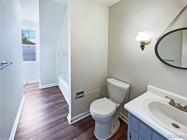 bathroom featuring hardwood / wood-style flooring, vanity, toilet, and a tub