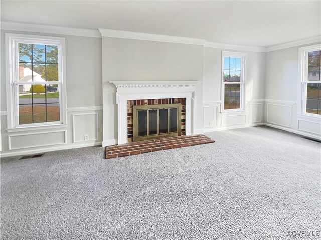 unfurnished living room with carpet, crown molding, a wealth of natural light, and a fireplace