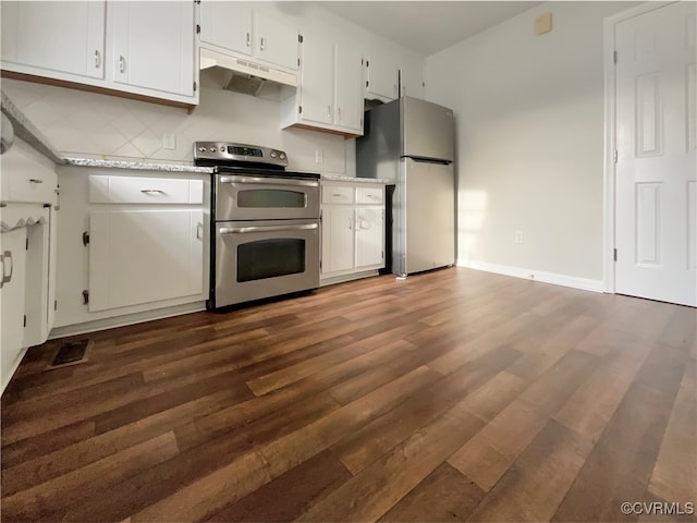 kitchen with appliances with stainless steel finishes, dark hardwood / wood-style flooring, white cabinetry, and backsplash