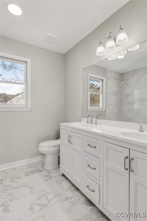 bathroom featuring vanity, a healthy amount of sunlight, and toilet