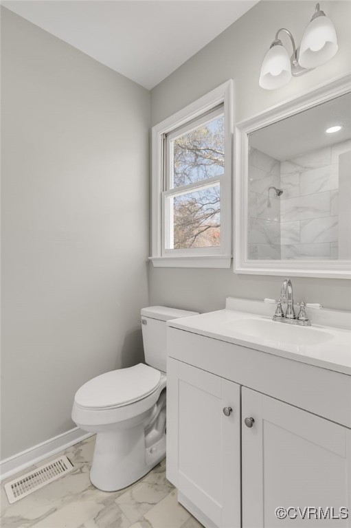 bathroom featuring a tile shower, vanity, and toilet