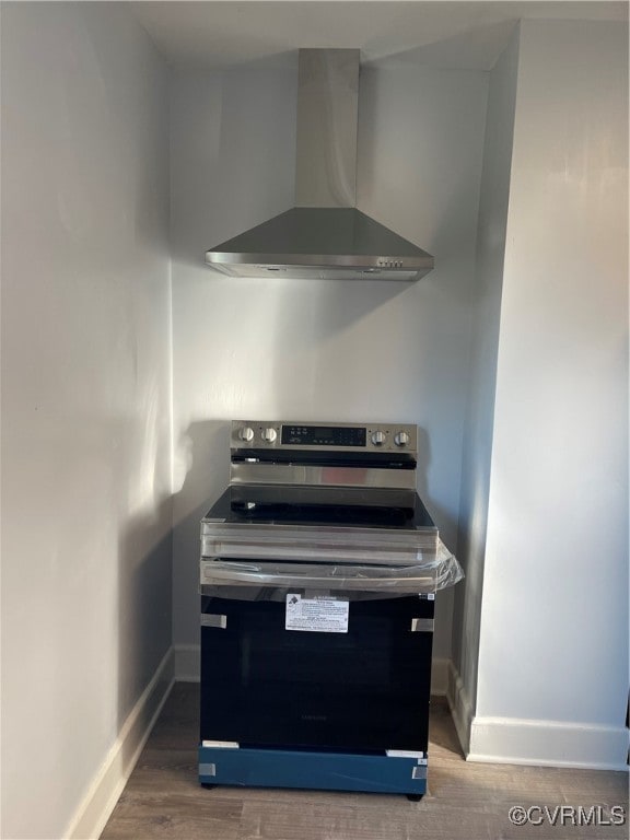 interior details featuring stainless steel electric stove, hardwood / wood-style floors, and wall chimney range hood