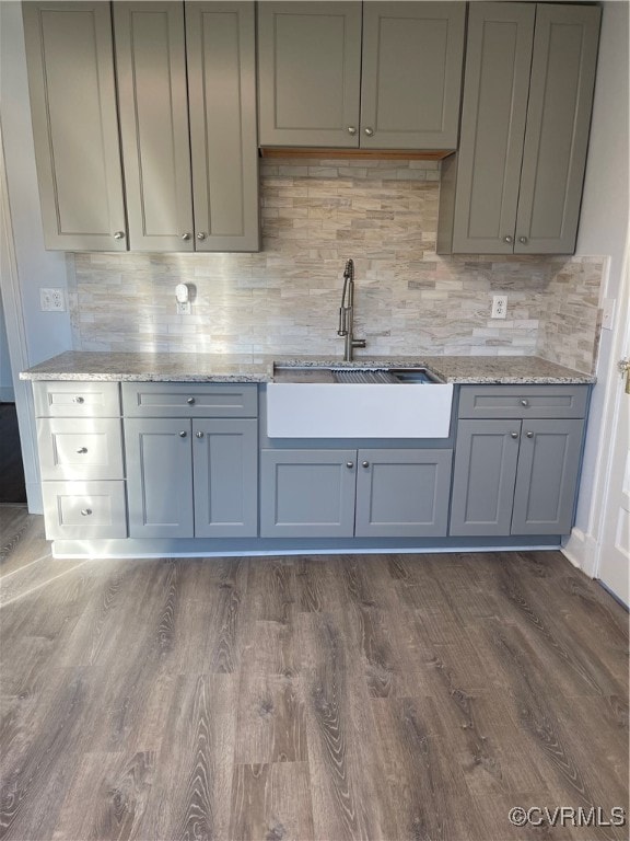 kitchen with light stone countertops, dark hardwood / wood-style floors, gray cabinetry, and sink