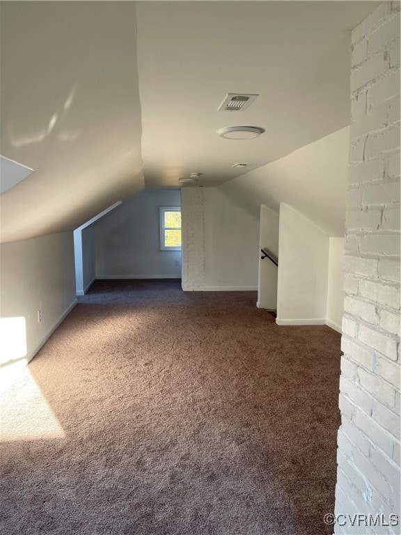 additional living space with dark colored carpet and lofted ceiling