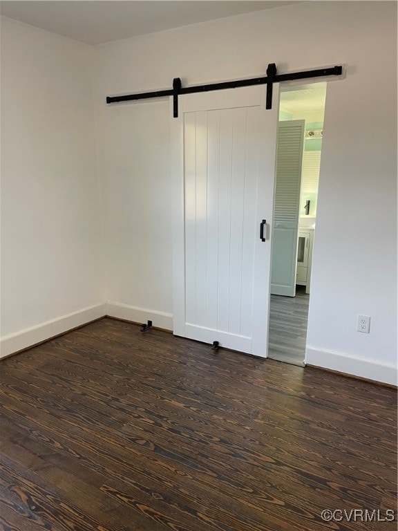 empty room with a barn door and dark hardwood / wood-style flooring