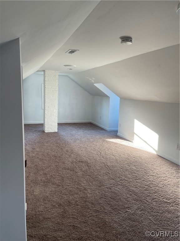 additional living space featuring dark colored carpet and lofted ceiling