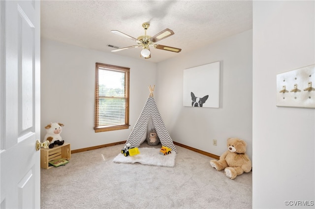 playroom featuring carpet flooring, ceiling fan, and a textured ceiling