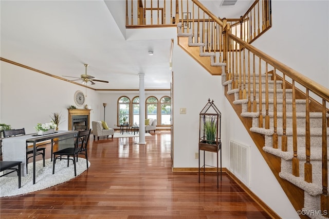 staircase with ornate columns, ceiling fan, ornamental molding, and hardwood / wood-style flooring