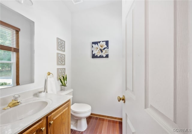 bathroom with hardwood / wood-style floors, vanity, a healthy amount of sunlight, and toilet