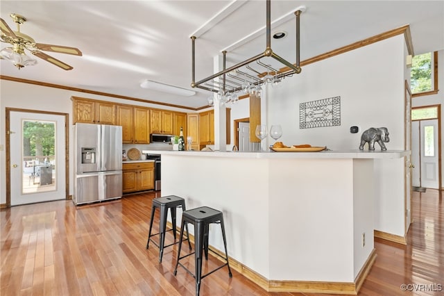 kitchen with decorative light fixtures, appliances with stainless steel finishes, light hardwood / wood-style floors, and plenty of natural light