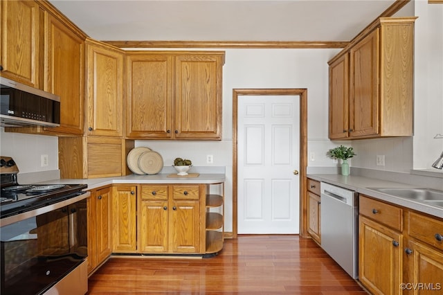 kitchen with appliances with stainless steel finishes, light wood-type flooring, and sink