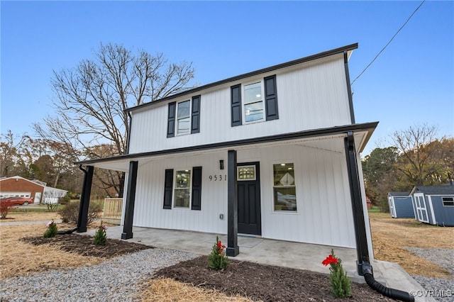 view of front of property with a porch and a storage shed