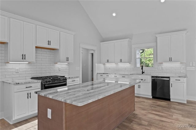 kitchen with white cabinetry, a kitchen island, black appliances, and light stone countertops