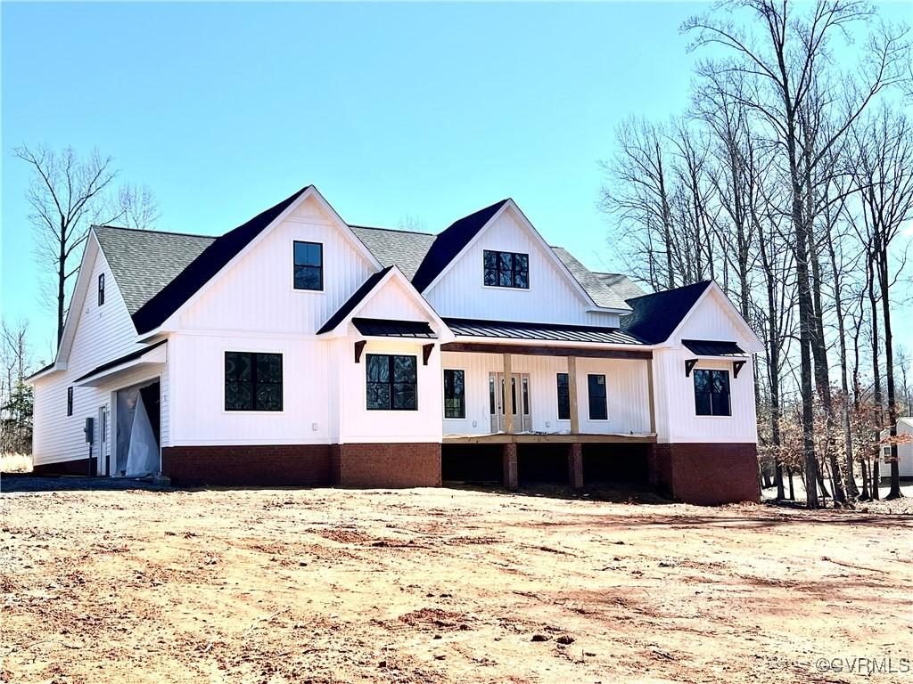 rear view of house featuring a standing seam roof, a shingled roof, and metal roof