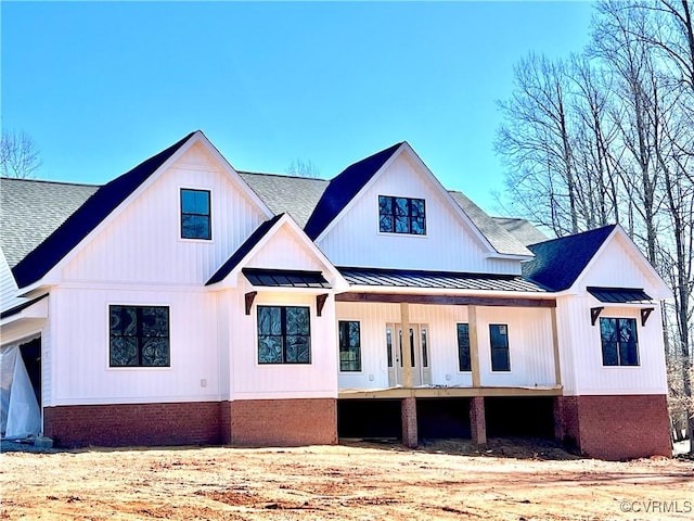 rear view of property featuring a shingled roof, a standing seam roof, and metal roof