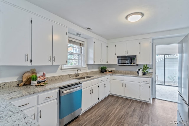 kitchen featuring white cabinets, sink, appliances with stainless steel finishes, dark hardwood / wood-style flooring, and light stone counters