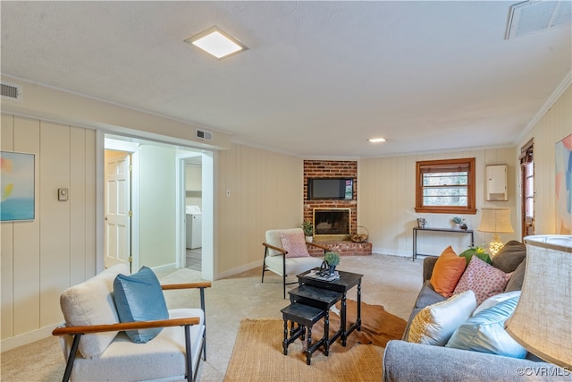 carpeted living room featuring crown molding, a fireplace, and washer / dryer