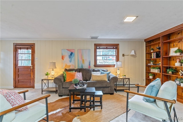 living room with light colored carpet, a baseboard radiator, and wooden walls