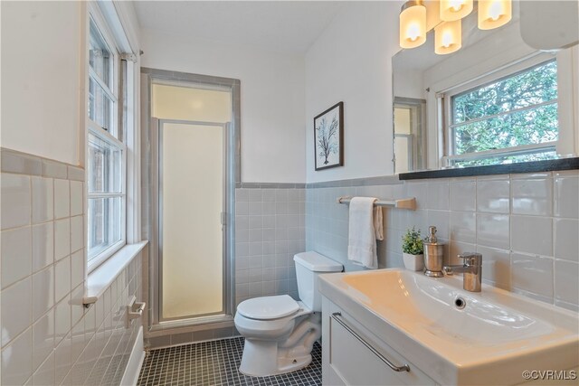 bathroom with vanity, tile patterned flooring, toilet, tile walls, and a shower with shower door