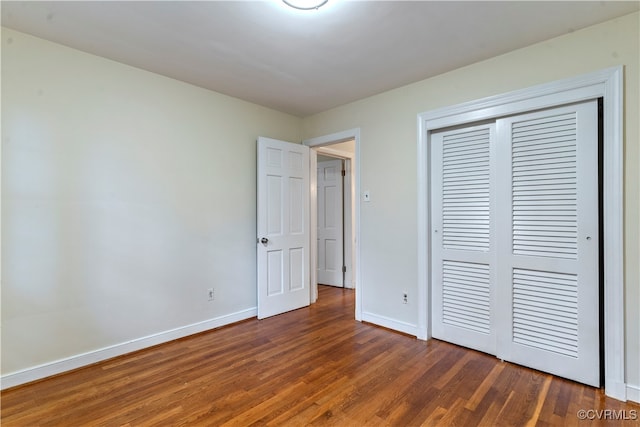 unfurnished bedroom with a closet and dark hardwood / wood-style floors