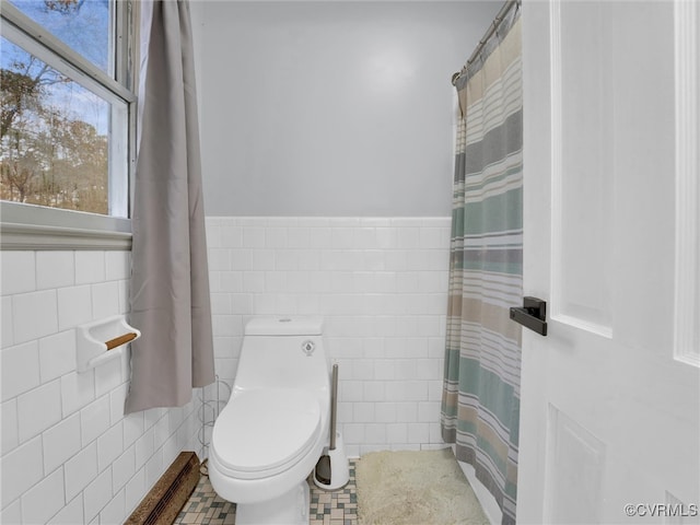 bathroom featuring tile patterned flooring, toilet, and tile walls