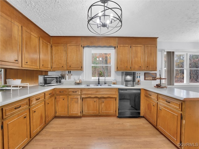 kitchen featuring dishwasher, sink, decorative light fixtures, and light hardwood / wood-style flooring