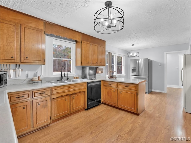 kitchen with sink, appliances with stainless steel finishes, decorative light fixtures, light hardwood / wood-style floors, and kitchen peninsula