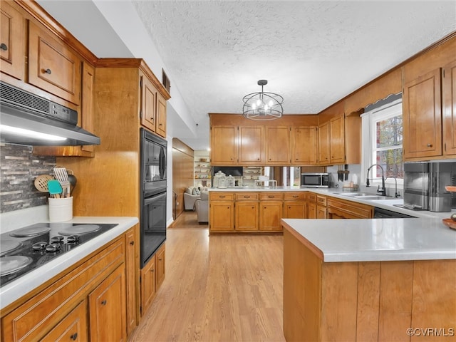 kitchen with sink, hanging light fixtures, white stovetop, light hardwood / wood-style floors, and exhaust hood