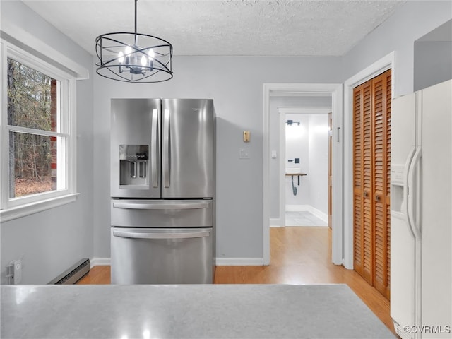 kitchen featuring stainless steel fridge, an inviting chandelier, light hardwood / wood-style flooring, white fridge with ice dispenser, and hanging light fixtures