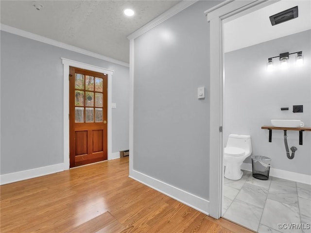 bathroom with hardwood / wood-style flooring, toilet, crown molding, and a textured ceiling