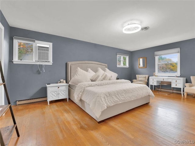 bedroom with light wood-type flooring and a baseboard radiator