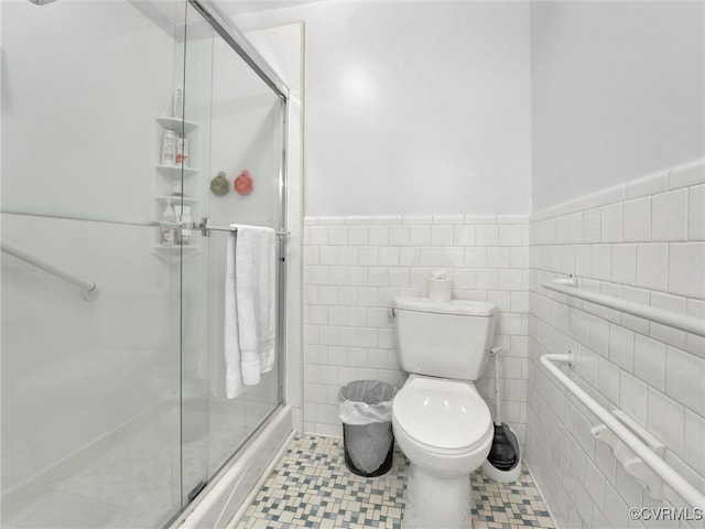 bathroom with tile patterned floors, a shower with door, tile walls, and toilet