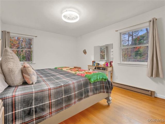 bedroom with hardwood / wood-style flooring and baseboard heating