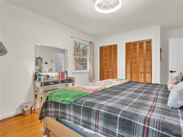 bedroom featuring hardwood / wood-style floors and two closets