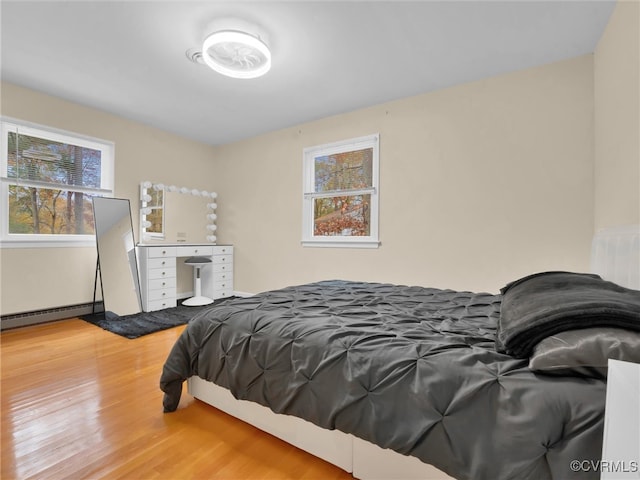 bedroom with hardwood / wood-style floors and baseboard heating