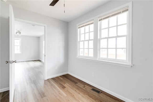 spare room with ceiling fan, a healthy amount of sunlight, and light hardwood / wood-style flooring