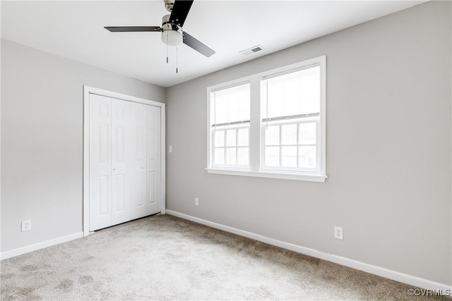 unfurnished bedroom featuring ceiling fan, light colored carpet, and a closet