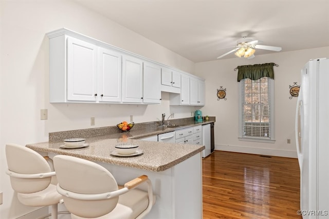 kitchen with white appliances, sink, kitchen peninsula, ceiling fan, and white cabinetry