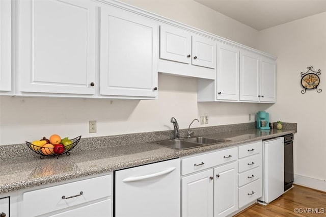 kitchen with white cabinetry, sink, white dishwasher, and light hardwood / wood-style flooring