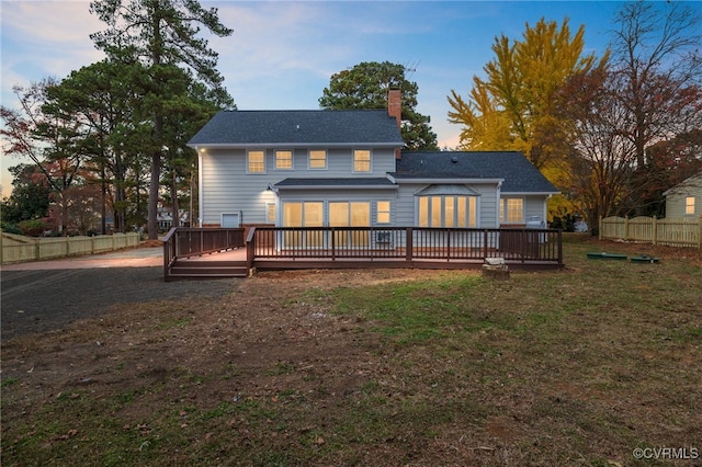 back house at dusk featuring a yard and a wooden deck