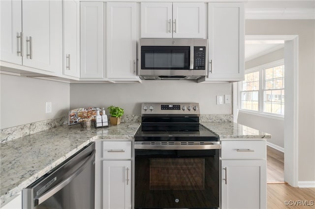 kitchen featuring light stone countertops, stainless steel appliances, light wood-type flooring, crown molding, and white cabinetry